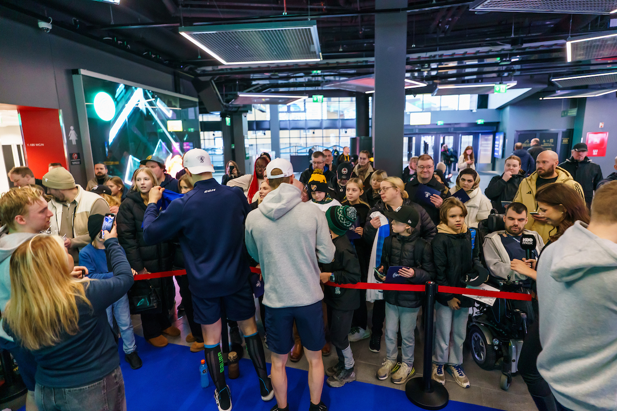 Ihmisiä jääkiekkoilijan nimmaria hakemassa.