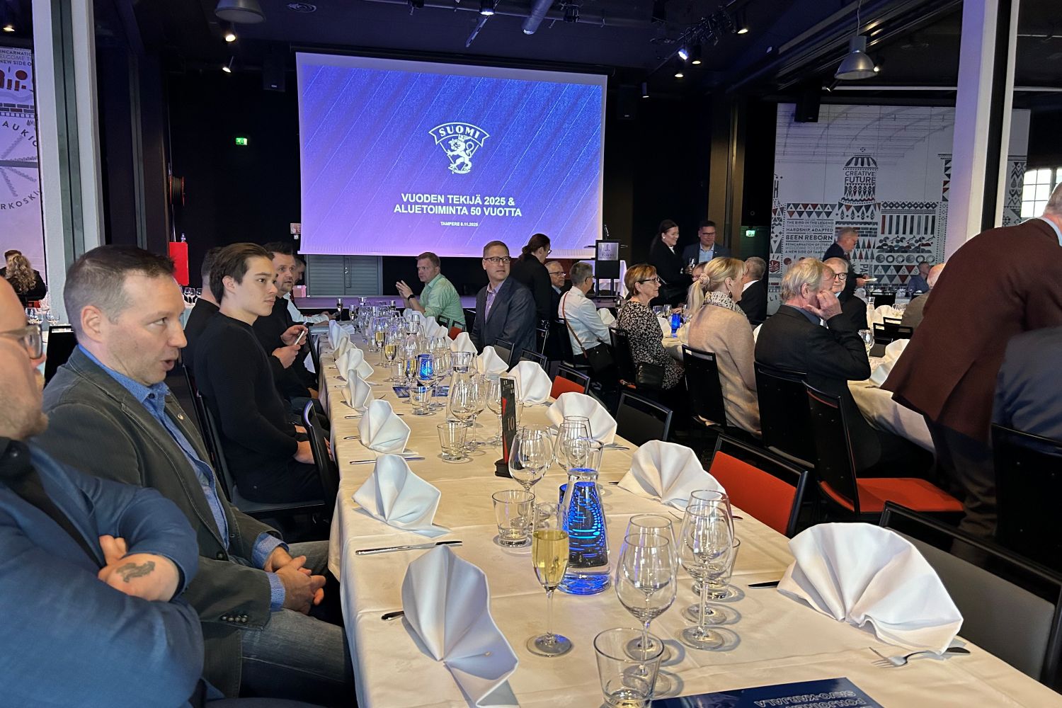 Ihmisiä juhlapöydän ääressä.